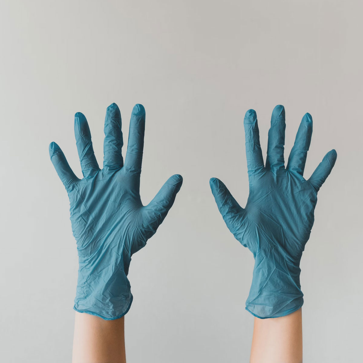 Two hands with blue surgical gloves on.