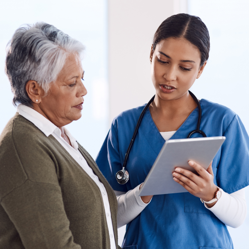 A nurse showing a patient their documentation on a tablet.