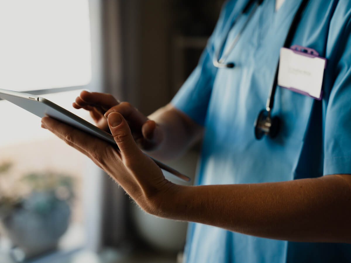 A healthcare professional holding an tablet and inputing information.