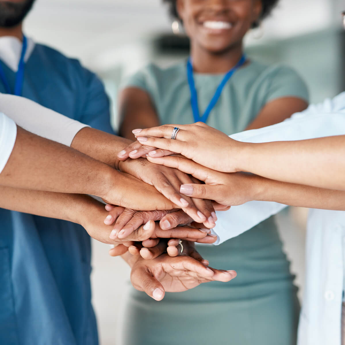 Close-up of healthcare worker's hands stacked together, symbolizing teamwork.