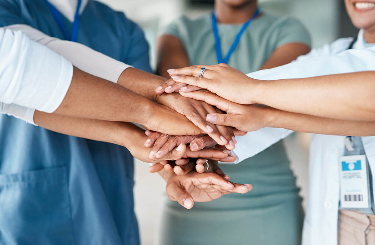 Close-up of healthcare worker's hands stacked together, symbolizing teamwork.